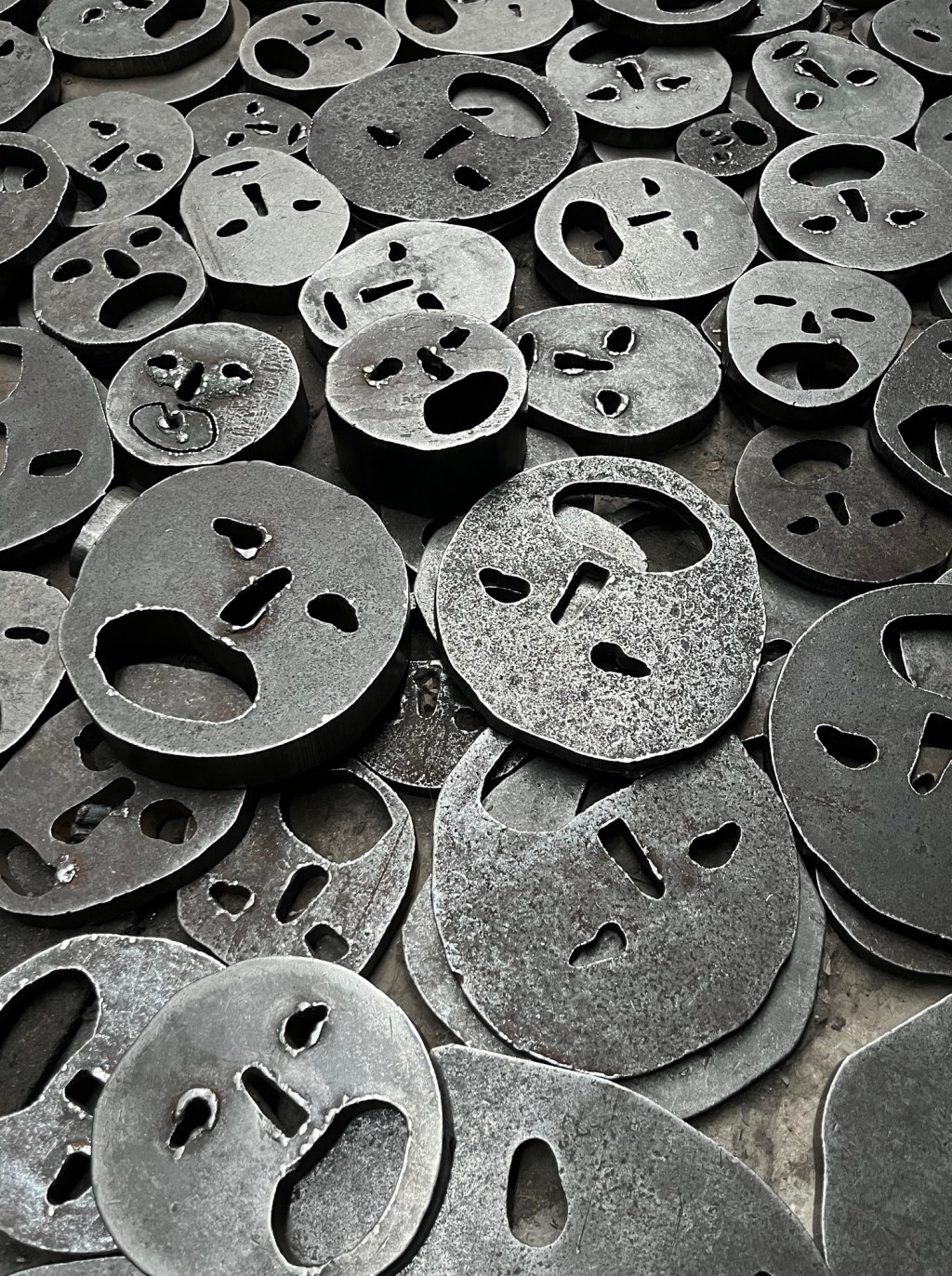 Photograph of the 'Shalekhet' Memorial from the Jewish Museum in Berlin. This installation displays metallic plates representing minimalist, deinvididualised faces. It represents the loss of individual identity and therefore the dehumanisation suffered by victims of the Shoah.
